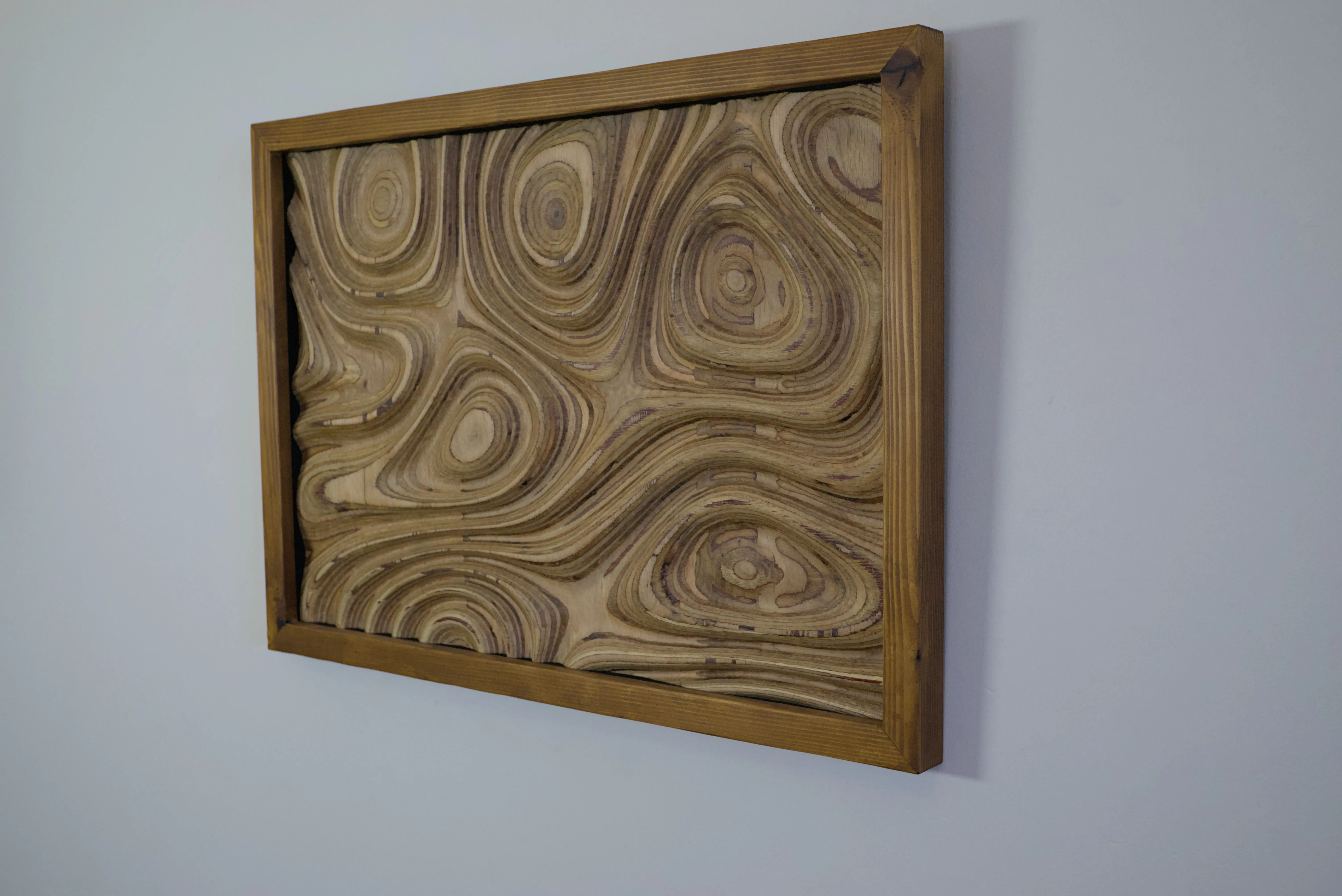 A contoured plywood surface in a timber frame viewed at an angle.