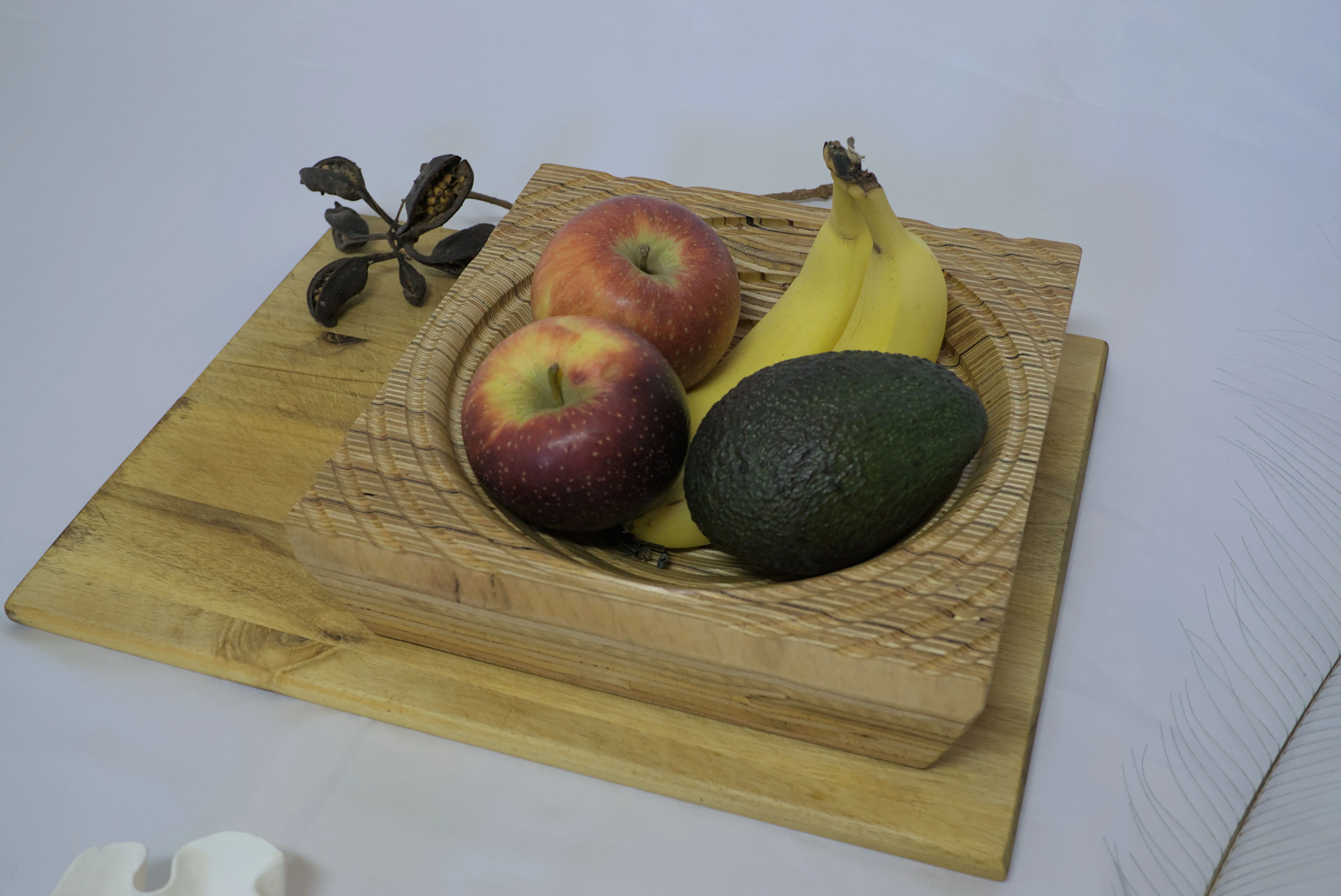 A plywood bowl with spiral groove filled with fruit.