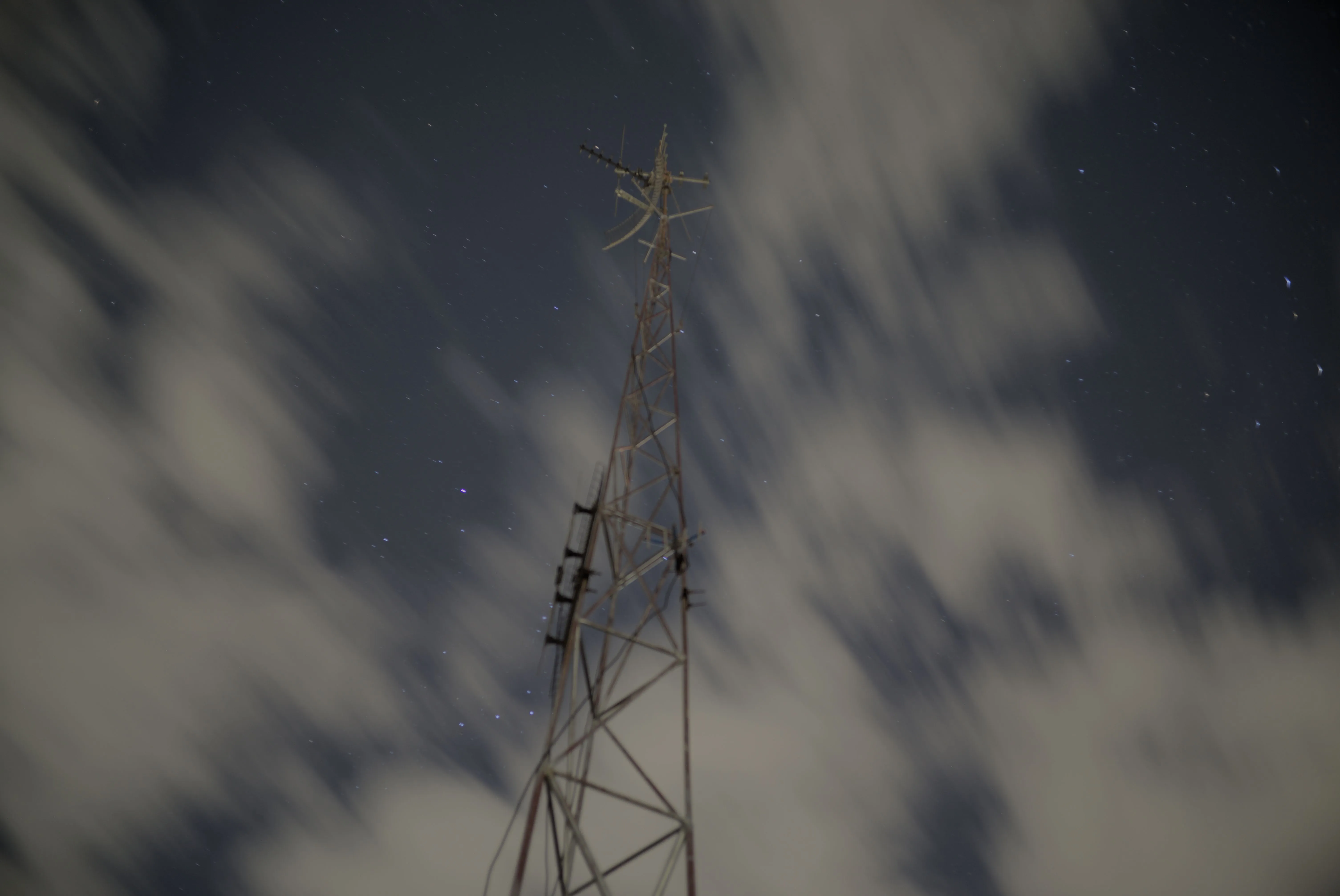 Long exposure night photo with a tower in focus and clouds behind it with motion blur
